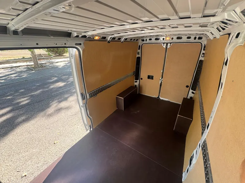 Zona de carga vista desde la puerta lateral, con suelo de tablero y raíles